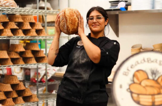 Owner Leslie holding up a loaf of bread in her commercial kitchen.