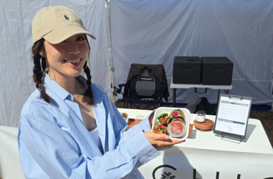 Woman holding up sliced kimbap.